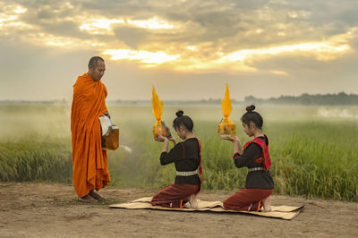 People on field against sky during sunset