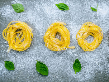 High angle view of spaghetti with herbs and flour on table