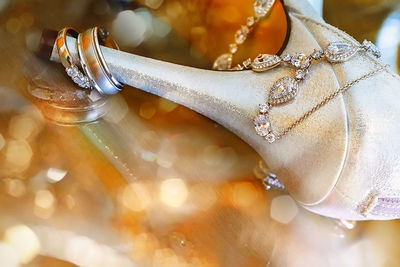 Close-up of wedding rings and high heels over illuminated lights