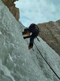 Rear view of man climbing on snow covered mountain