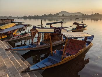 Boats moored in lake against sky during sunset