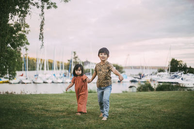 Full length of mother and daughter on grass against sky