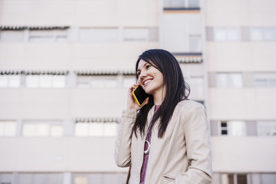 Young woman looking away while standing on mobile phone