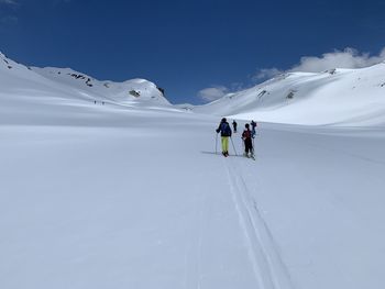 People skiing on snowcapped mountain against sky