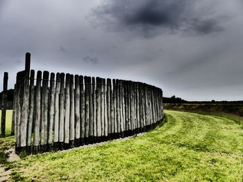 Wooden fence on field against sky