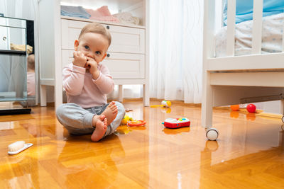 Boy playing with toy blocks while sitting on floor at home