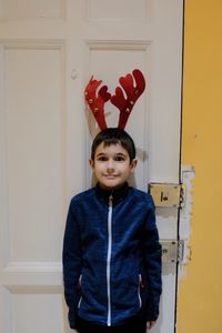 Portrait of smiling boy standing against door
