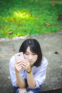 Portrait of woman holding smart phone while sitting outdoors