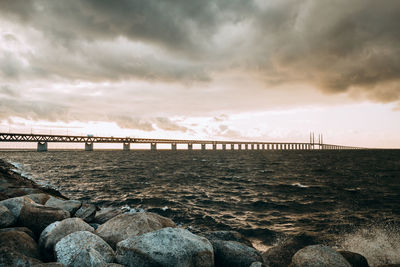 Bridge over sea against sky during sunset