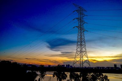 Low angle view of silhouette electricity pylon against sky at sunset