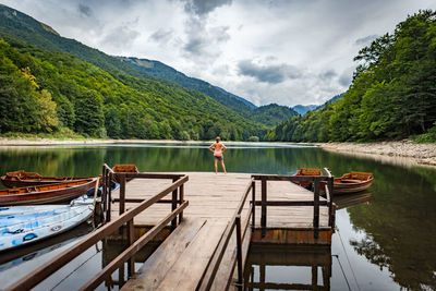 Rear view of woman standing on pier over lake