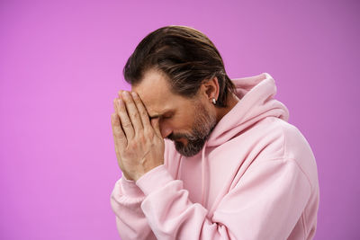 Portrait of young man against pink background