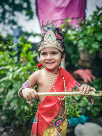 Portrait of smiling child standing against trees in krishna get-up