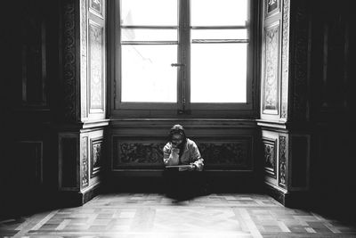 Rear view of man sitting in front of window
