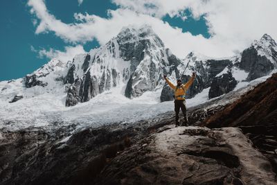 Woman walking on snow covered mountain against sky