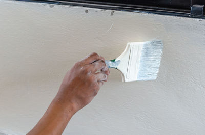 Close-up of hand against white wall at home