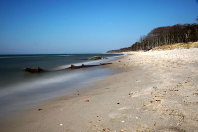 Scenic view of beach against clear blue sky