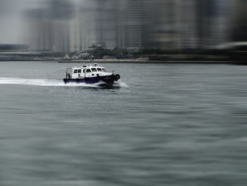 Boat in river against blurred buildings