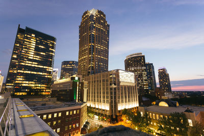 Skyscrapers in city against sky at dusk