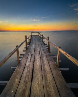 Pier over sea against sky during sunset