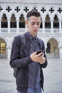 Teenage girl looking away while standing on mobile phone