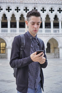 Teenage guy looking away while standing on mobile phone