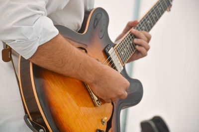 Midsection of man playing guitar at home