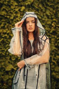 Young beautiful woman in hooded raincoat on rainy day