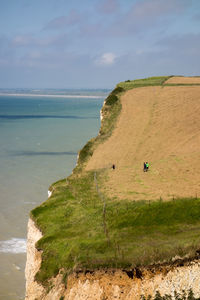 Scenic view of sea by cliff against sky