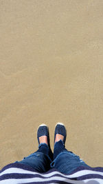Low section of man standing on sand