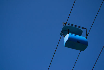 Low angle view of overhead cable car against blue sky