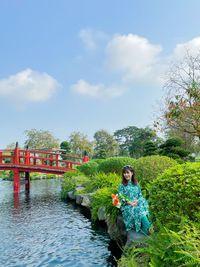 Woman standing on bridge over canal against sky