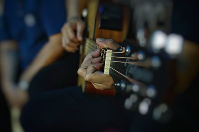 Midsection of man playing guitar