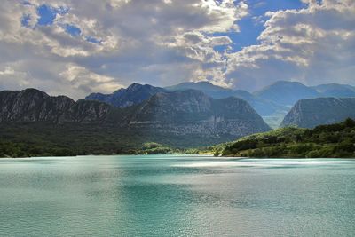 Scenic view of lake by mountains against sky