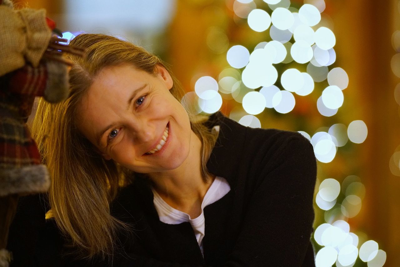 smiling, portrait, happiness, emotion, one person, christmas, women, headshot, young women, young adult, illuminated, focus on foreground, hair, lifestyles, real people, beauty, looking at camera, christmas tree, celebration, beautiful woman, hairstyle