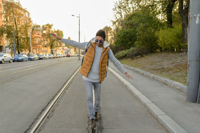 Young man walking on railroad track on street