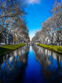 Canal amidst trees against clear blue sky
