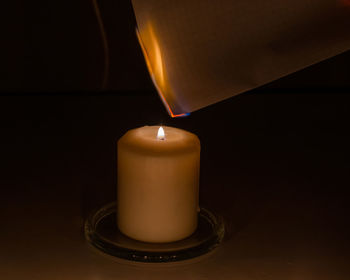 Close-up of illuminated tea light candle in darkroom