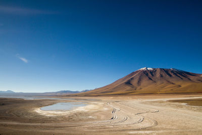 Scenic view of arid landscape against clear blue sky