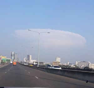 Cars on highway in city against sky