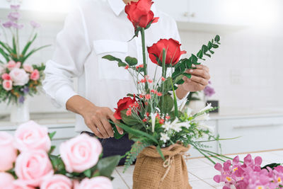 Midsection of woman holding rose bouquet on table