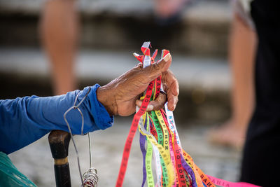 Hands of a street vendor holding souvenir ribbons during open mass at the senhor do bondim church