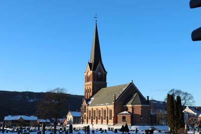 Church by building against clear blue sky