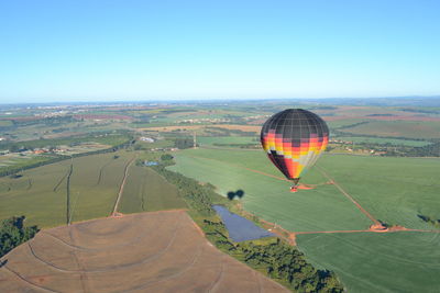 Hot air balloon flying over land against clear sky