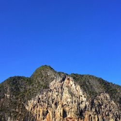 Low angle view of rocky mountains against clear blue sky