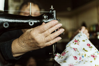 Close-up of old woman using sewing machine