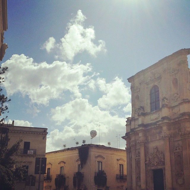 architecture, building exterior, built structure, sky, low angle view, sunlight, building, cloud - sky, city, window, cloud, sunbeam, day, residential building, sun, outdoors, church, residential structure, history, no people