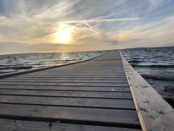 Pier over sea against sky during sunset