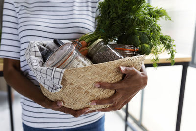 Woman carrying basket with fresh organic food in sustainable packaging