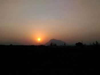 Silhouette field against sky during sunset